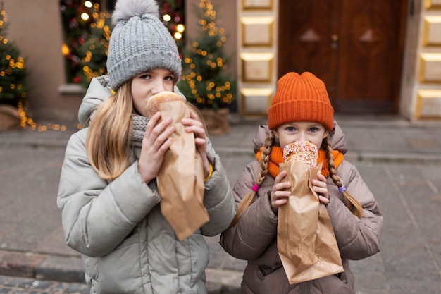 Little girls tasting a sweet on their winter holidays