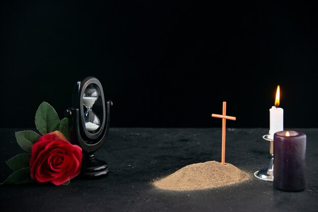 Little grave with candle and flower as memory on a dark surface