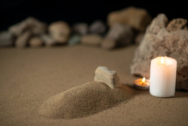 Little grave with candle and stones on sand funeral war death