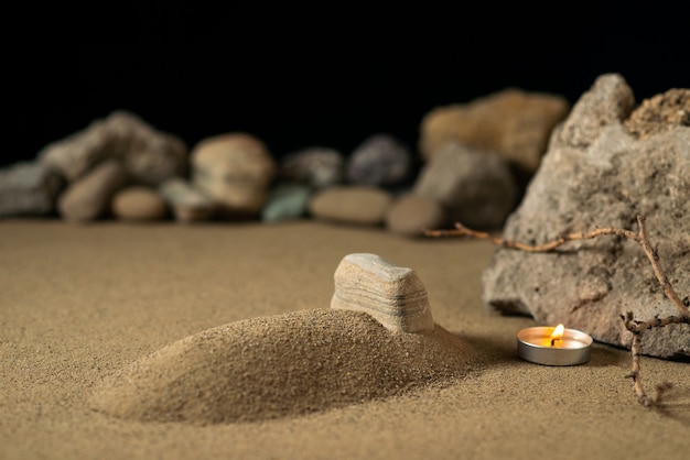 Little grave with candle and stones on sand funeral war
