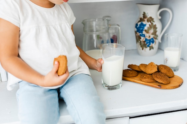 Little hands holding cookie and a glass of milk
