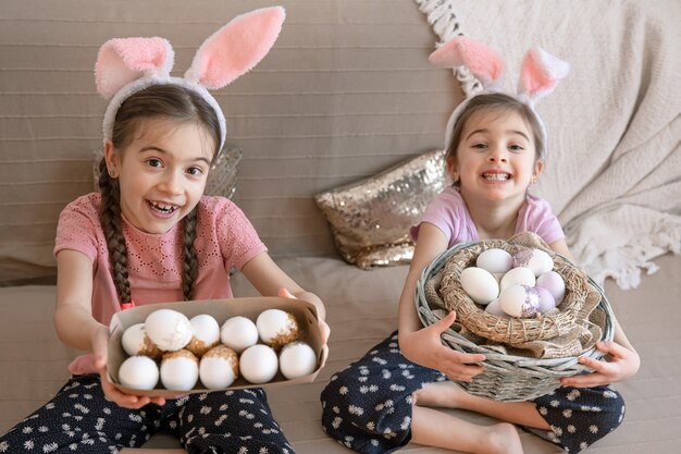 Little happy sisters with bunny ears, with Easter eggs