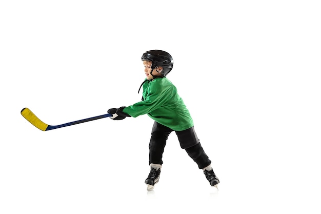 Little hockey player with the stick on ice court, white background. Sportsboy wearing equipment and helmet, practicing, training.
