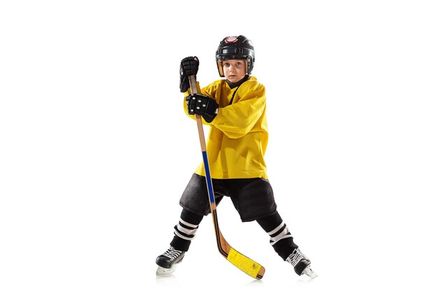 Little hockey player with the stick on ice court and white studio wall