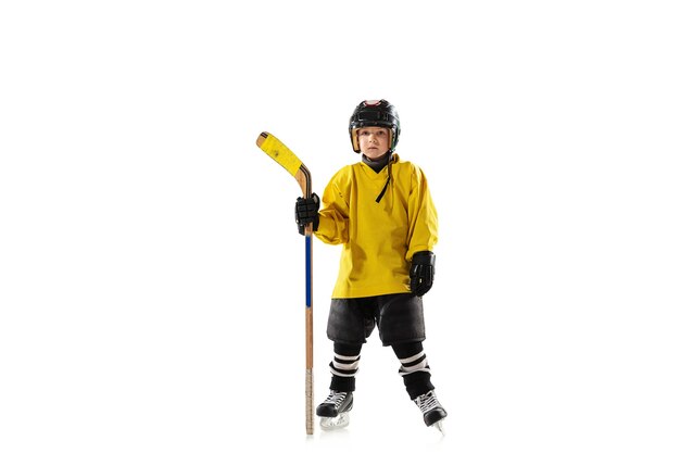 Little hockey player with the stick on ice court and white studio wall