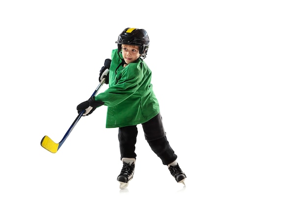 Foto gratuita piccolo giocatore di hockey con il bastone sul campo da ghiaccio, muro bianco. sportsboy che indossa attrezzatura e casco, pratica, allenamento. concetto di sport, stile di vita sano, movimento, movimento, azione.