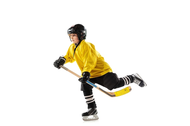 Маленький хоккеист с клюшкой на ледовой площадке и белый