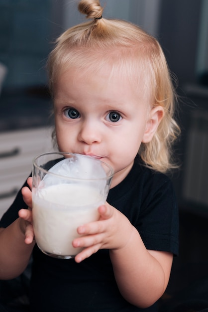 Маленький ребенок пьет молоко на кухне
