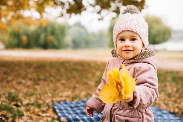 Little kid holding pack of leaves in autumn forest