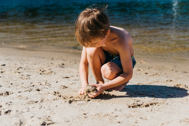 Маленький ребенок играет на пляже во время летних каникул