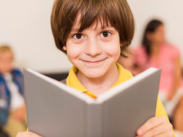 Foto gratuita ragazzino che sorride mentre si tiene un libro