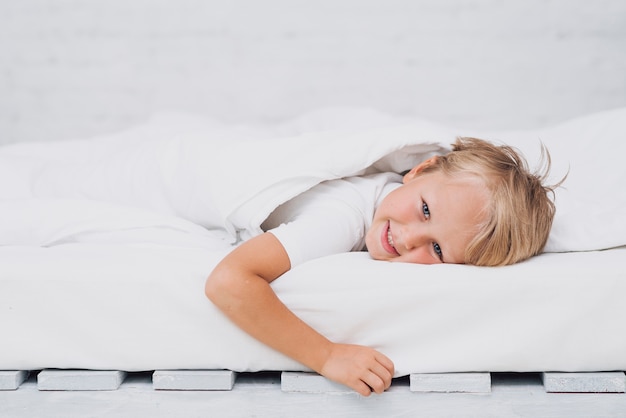 Little kid staying in bed while looking at the camera