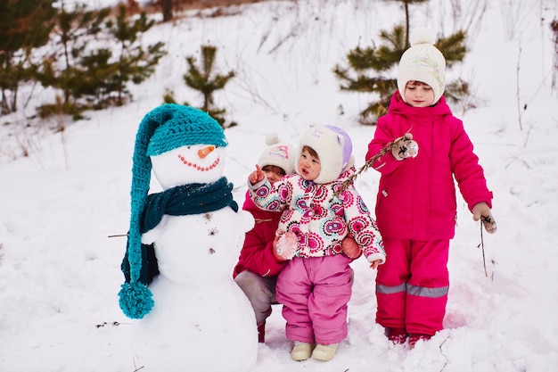 小さな子供たちは美しい雪だるまを見ています