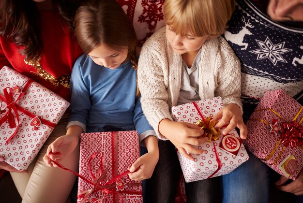 Маленькие дети готовы открывать рождественские подарки