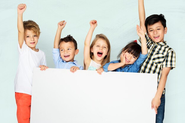 Little kids cheering while holding a white board