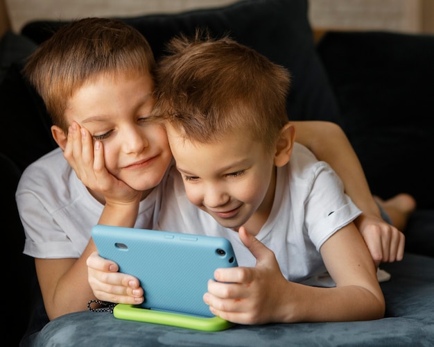 Маленькие дети вместе смотрят по телефону дома