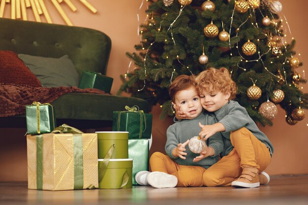 灰色のセーターでクリスマスツリーの近くの小さな子供たち