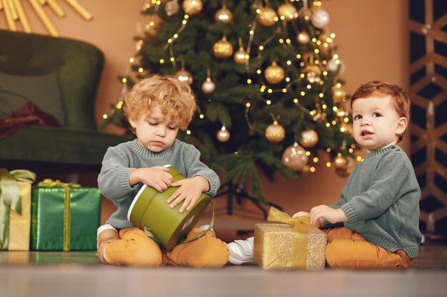 Little kids near christmas tree in a gray sweater
