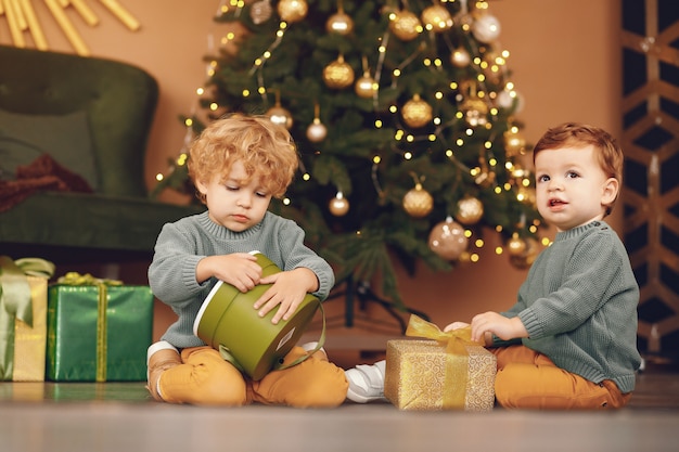 灰色のセーターでクリスマスツリーの近くの小さな子供たち