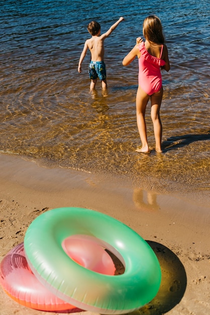 小さな子供たちがビーチで水で遊ぶ