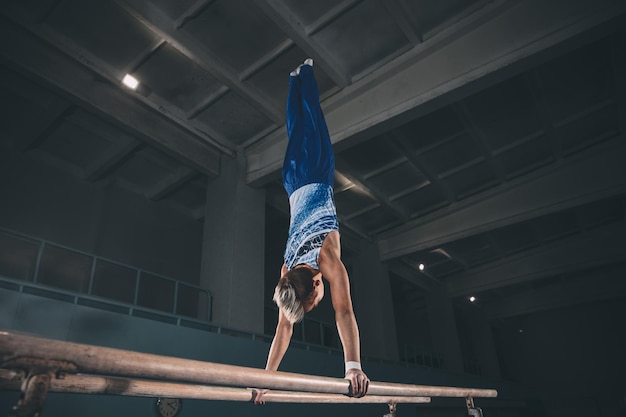 Little male gymnast training in gym flexible and active Caucasian fit little boy athlete in sportswear practicing in exercises for strength balance