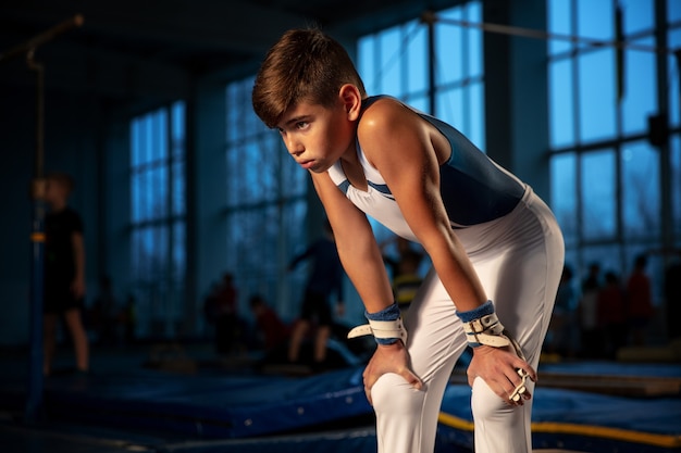 Little male gymnast training in gym, flexible and active