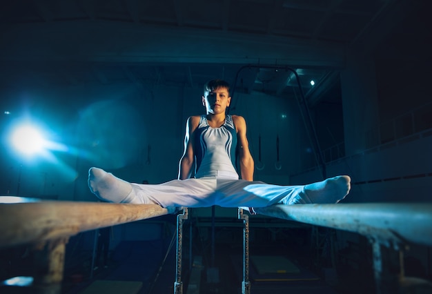 Little male gymnast training in gym, flexible and active