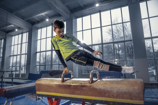 Free photo little male gymnast training in gym, flexible and active