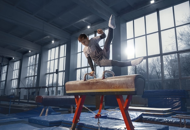 Free photo little male gymnast training in gym, flexible and active