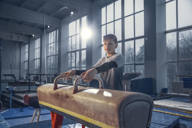 Free photo little male gymnast training in gym, flexible and active