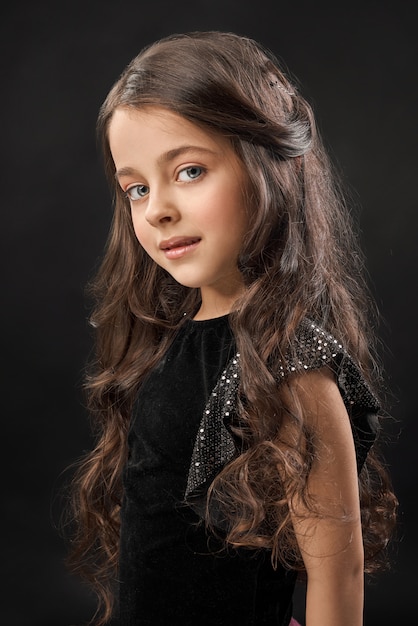 Little model in black dress on black background.