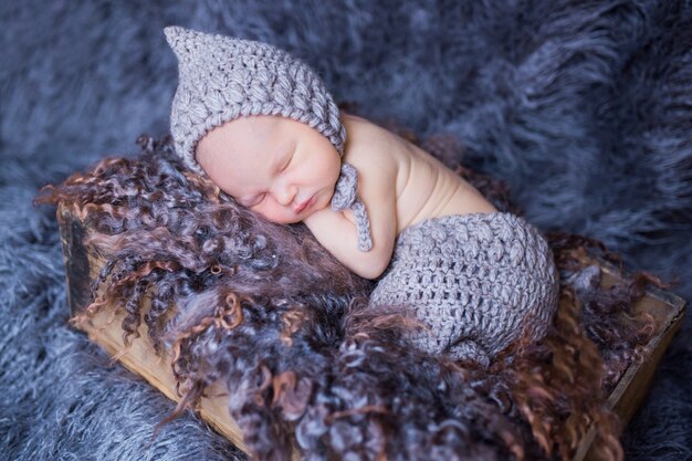 Little newborn baby in knitted clothes sleeps on the pillow
