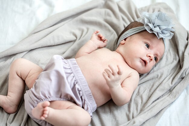 Little newborn baby with a bandage on his head lies on a soft blanket.