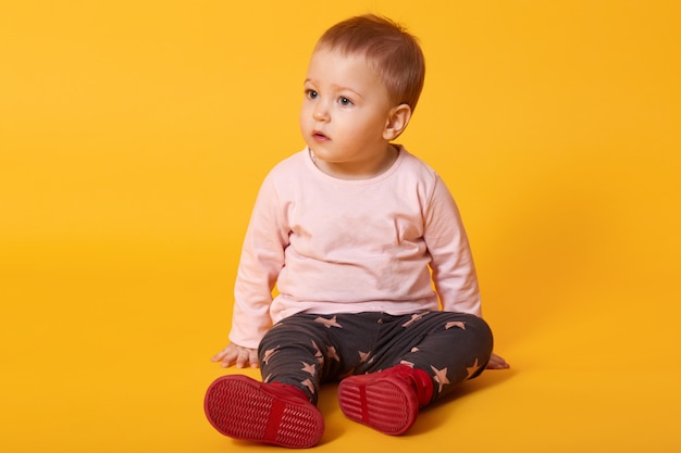 Little pretty girl sits on floor, dressed sweater