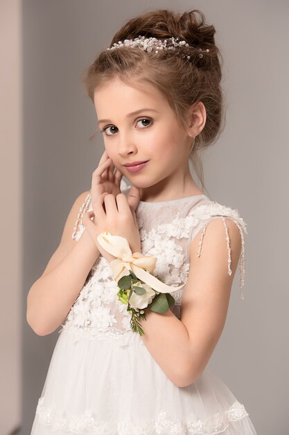 Little pretty girl with flowers dressed in wedding dresses