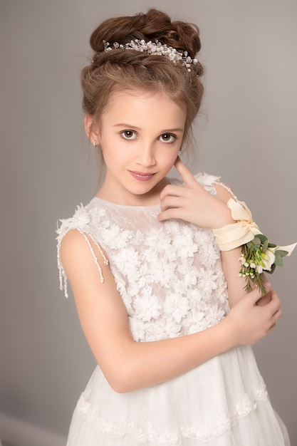 Little pretty girl with flowers dressed in wedding dresses