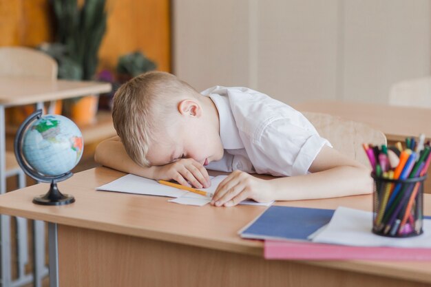 Little pupil laying on table in classroom