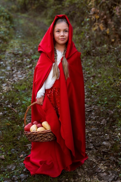 Free photo little red riding hood with wooden basket with goodies