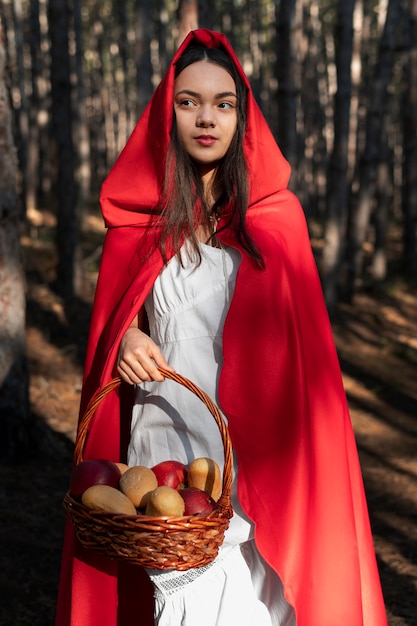 Free photo little red riding hood with wooden basket with goodies