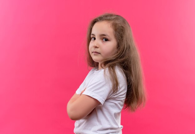 little school girl wearing white t-shirt crossing hands on isolated pink wall