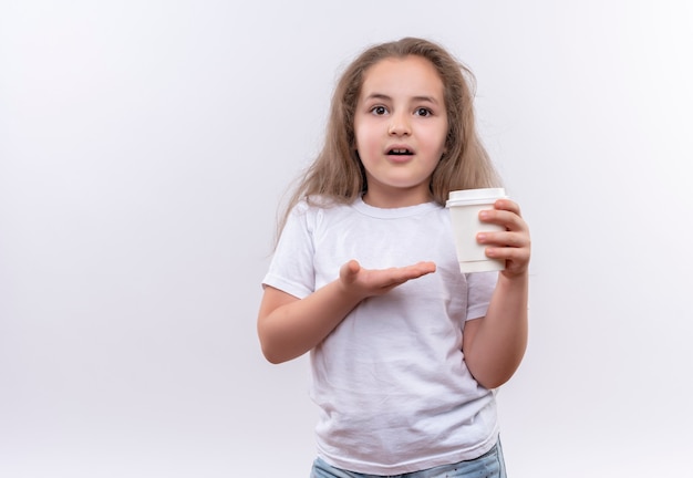 Бесплатное фото Маленькая школьница в белой футболке держит чашку кофе на изолированной белой стене