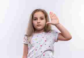 Free photo little school girl wearing white t-shirt raising hand on isolated white wall