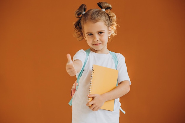 Free photo little school girl with notebook and rucksack isolated in background