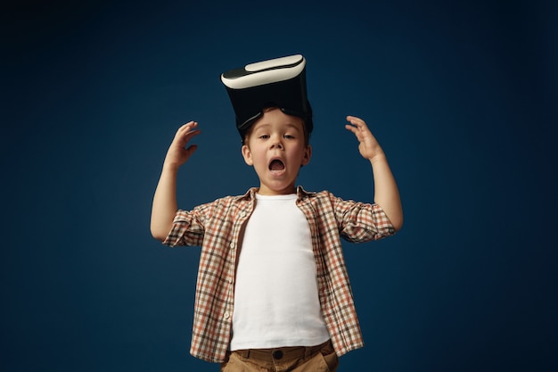 Little shocked boy wearing shirt with virtual reality headset