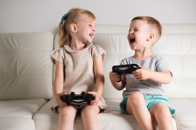 Free photo little siblings playing digital games with joystick