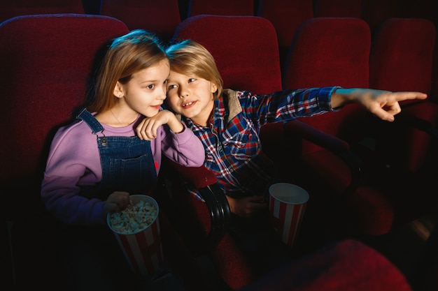 Little sister and brother watching a film at movie theater
