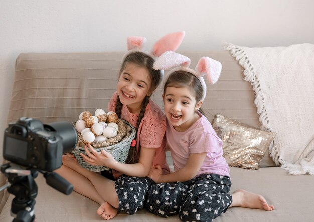 Little sisters in bunny ears pose for the camera with a basket of holiday eggs