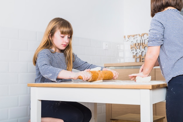 Little sisters cooking dough in kitchen