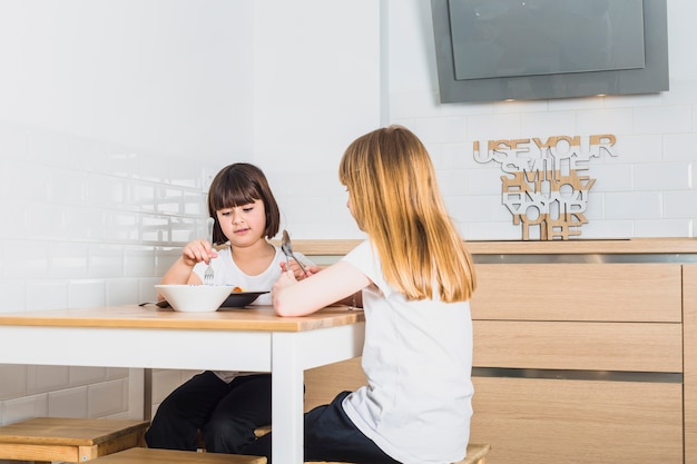 Little sisters sitting in kitchen