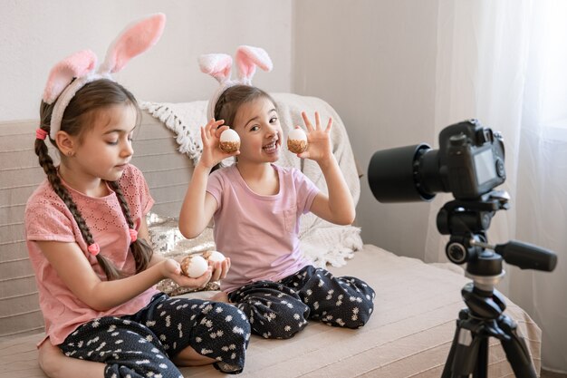 Piccole sorelle con orecchie da coniglio in posa per la fotocamera sul divano di casa